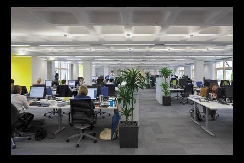 The open-plan offices are airy despite the low ceiling heights. The waffle slab is clearly visible.